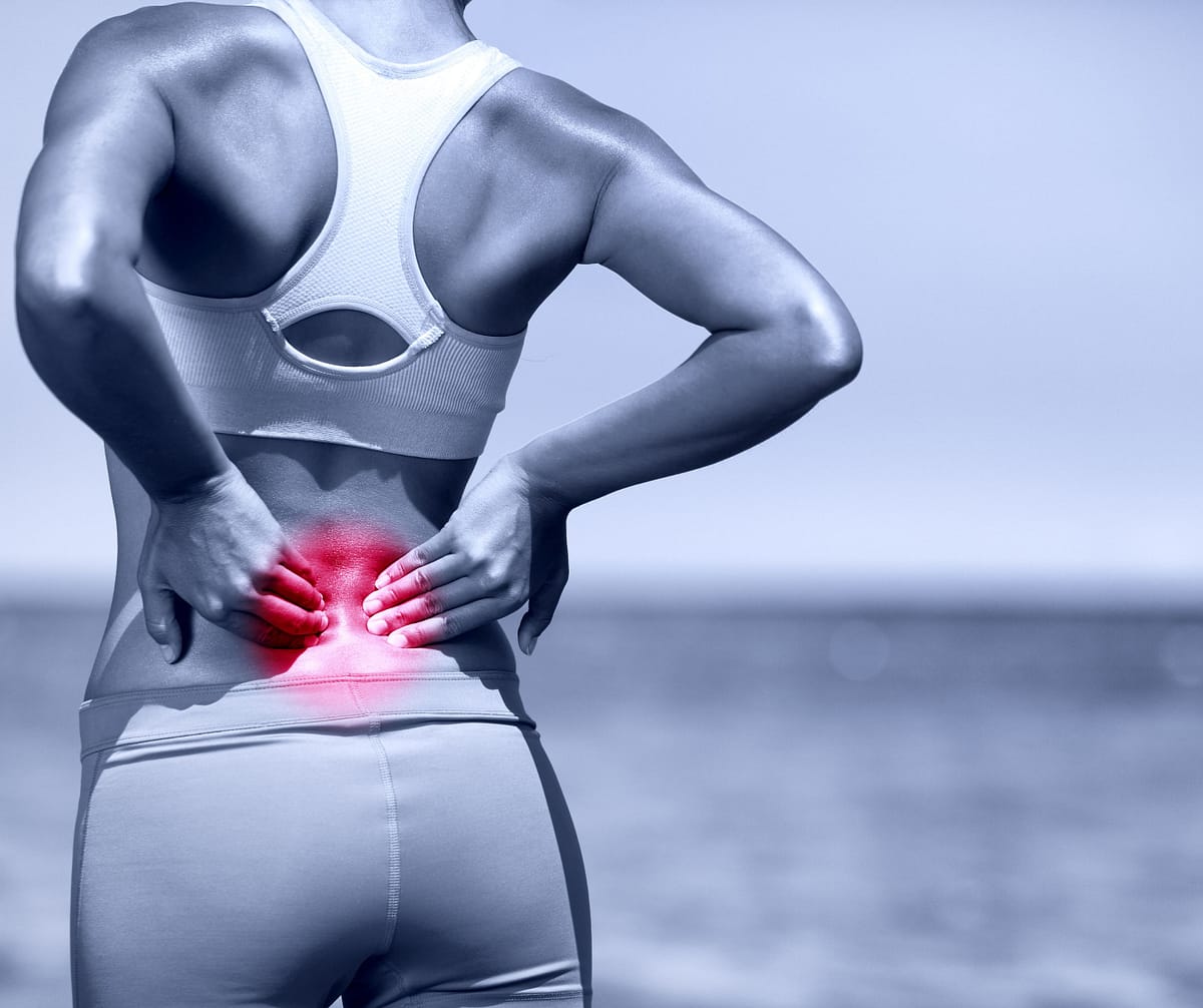 Mujer con dolor de espalda baja, indicando el uso de la crema antiinflamatoria para aliviar molestias musculares.
