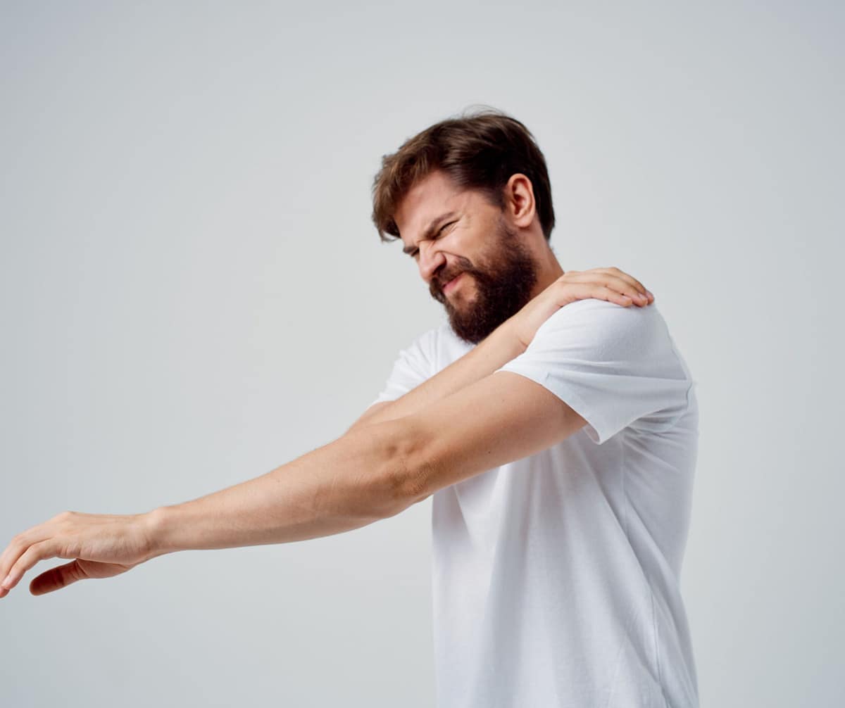 Hombre con dolor en el hombro, mostrando la necesidad de un alivio muscular con la crema antiinflamatoria.