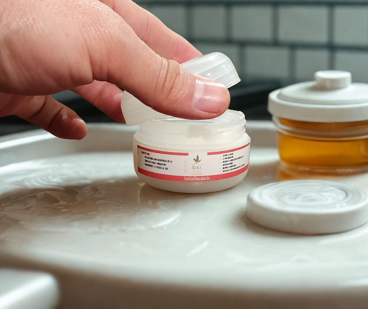 Mano abriendo el pote de Crema Antiinflamatoria de ozono, un producto esencial para el bienestar físico.