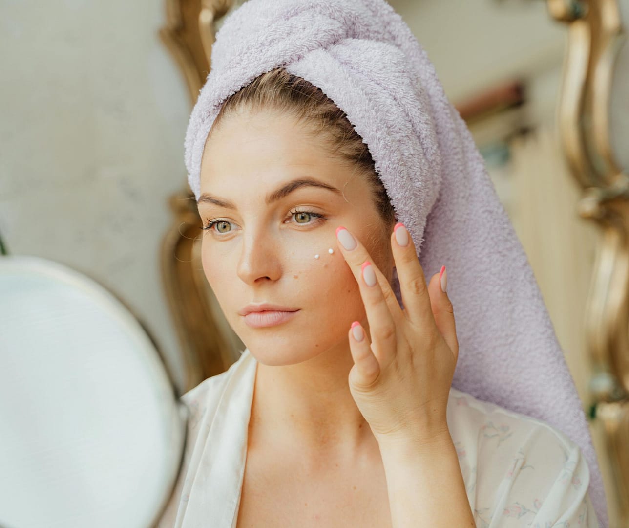 Mujer aplicando la crema despigmentante en su mejilla, mostrando el uso del producto para tratar manchas faciales y unificar el tono de la piel.