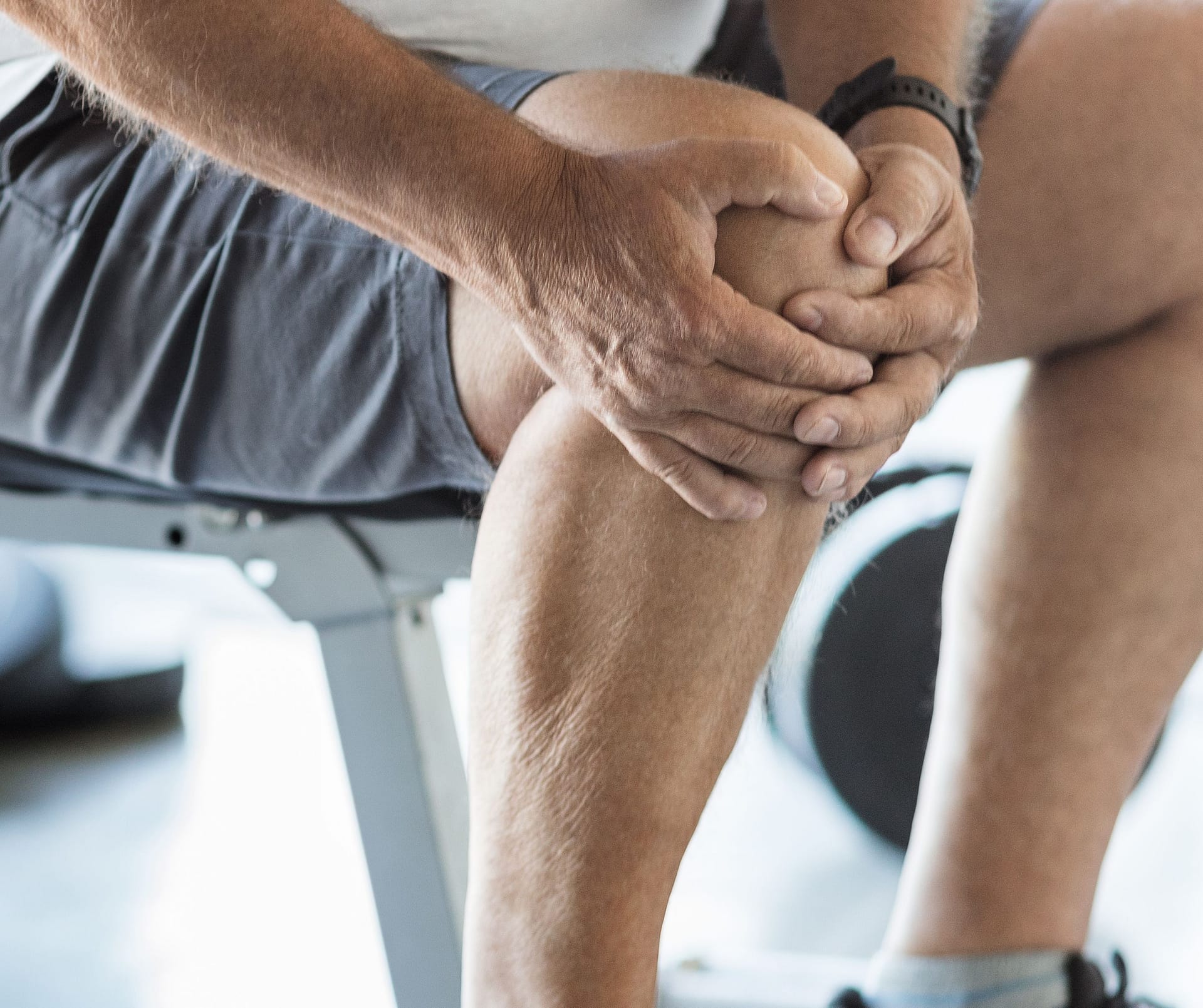 Hombre con dolor de rodilla, señalando el uso de la crema desinflamatoria para el cuidado de articulaciones.